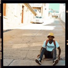 a man wearing a notorious t-shirt sits on the ground