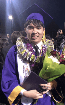 a man in a purple cap and gown holds a diploma