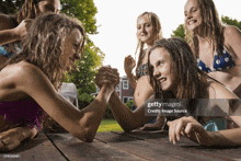 a group of young girls arm wrestling on a table