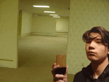 a young man is holding a glass of wine in front of an empty wall