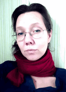 a woman wearing glasses and a scarf looks at the camera