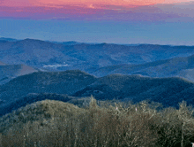 a view of the mountains with a pink sky in the background