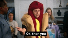 a man in a hot dog costume is talking to a woman in a room .