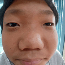 a close up of a young boy 's face with a gray shirt on