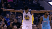 a basketball player in a golden state warriors uniform is celebrating with his arms outstretched during a game .