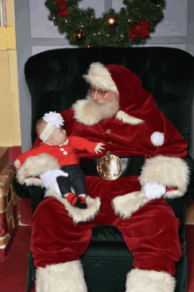 a baby is sitting on santa 's lap with a gold belt with a clock on it