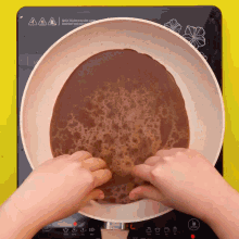 a person is stirring a brown liquid in a frying pan on a stove that has a warning label on it