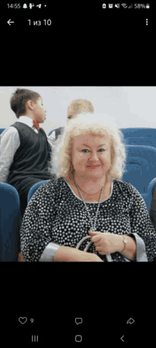 a woman in a black and white polka dot shirt sits in a row of blue seats