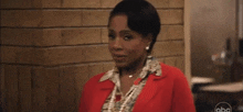 a woman is standing in front of a brick wall wearing a red jacket .