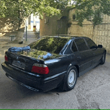 a black car is parked in front of a stone wall