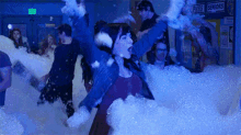 a group of people are playing in foam in a room .