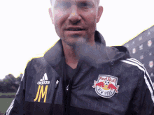 a man wearing a black adidas jacket with red bull new york on the front