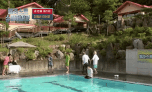 a group of people standing around a swimming pool with a sign in the background that says ' ep '