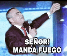 a man in a suit and tie is holding a microphone and says " señor manda fuego "