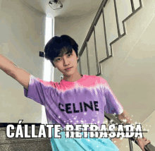 a man wearing a purple tie dye celine shirt stands in front of stairs