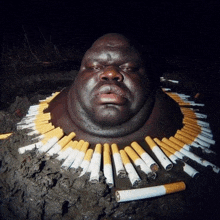 a man 's head is surrounded by cigarettes in the mud