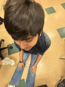 a young boy wearing a blue shirt and jeans is kneeling down