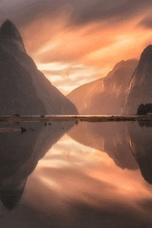 a lake with mountains in the background and a sunset sky