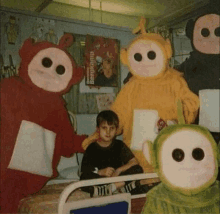 a child is sitting in a hospital bed surrounded by teletubbies and a poster that says bergkamp