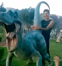 a man is standing next to a statue of a dinosaur with its mouth open