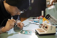 a man is working on a circuit board with a soldering iron