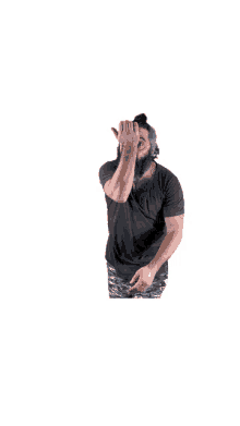 a man with a beard wearing a black t-shirt is covering his eyes with his hand