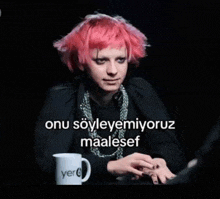 a woman with pink hair is sitting at a table with a mug that says yer