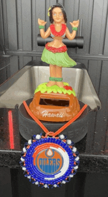 a hula girl figurine sits on top of a hockey puck that says hawaii