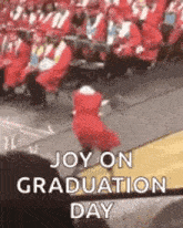 a girl in a red dress is dancing in front of a crowd of graduates at a graduation ceremony .