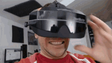 a man wearing a virtual reality headset is smiling and holding his hand up