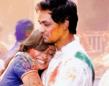 a man and a woman are hugging each other while covered in powder paint .