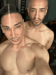 two shirtless men are posing for a selfie together