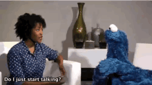 a woman sits in a chair talking to a cookie monster who says " do i just start talking "