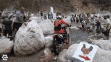 a man on a dirt bike is riding through a river surrounded by rocks .