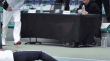 a man is laying on the ground in front of a table with a scoreboard and a bottle of water .