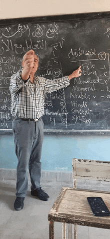 a man stands in front of a blackboard that has advanced written on it