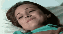 a woman in a green shirt is smiling while laying in a hospital bed