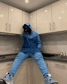 a person in a blue nike hoodie sits on a counter