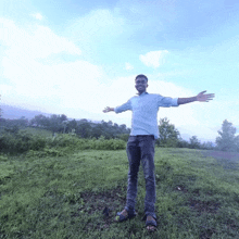 a man with his arms outstretched stands in a grassy field