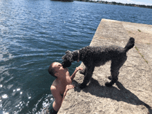 a dog licking a man 's face while they are near the water