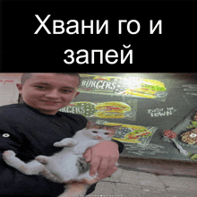 a boy holding a cat in front of a sign that says " burgers "