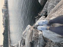 a person 's feet on a rock near the water