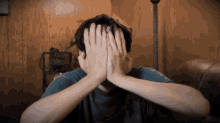 a person covering their face with their hands in a dark room