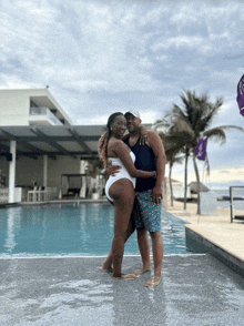 a man and a woman are posing for a picture by a pool