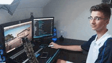 a young man is sitting at a desk playing a video game on a laptop .