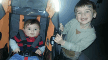 two young boys are standing next to a stroller with a baby in it