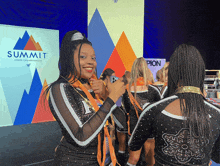 cheerleaders standing in front of a summit cheer championship banner