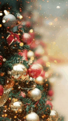 a close up of a christmas tree decorated with red and gold balls and lights .