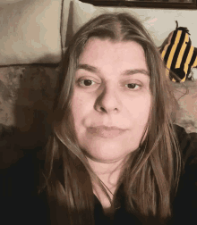 a woman sitting on a couch with a yellow and black striped bag in the background