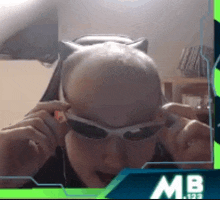 a man wearing sunglasses and a cat ear headband with the letters mb on the bottom